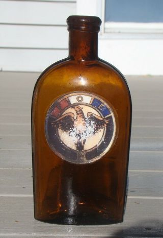 Antique F.  O.  E.  Eagle Labeled Strap Sided Amber Whiskey Flask